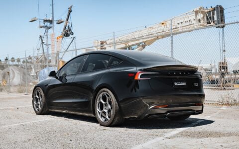 Tesla Model 3 Performance with 19-inch Satin Titanium UP-05 Forged Wheels by Unplugged Performance, parked in front of an industrial backdrop, highlighting the car’s sleek design and high-performance wheels.