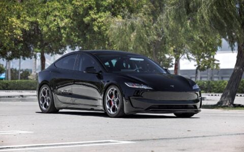 Front angle shot of a 2024 Tesla Model 3 Performance in black, equipped with 19-inch Satin Titanium UP-05 Forged Wheels by Unplugged Performance, captured in a sunny parking lot.