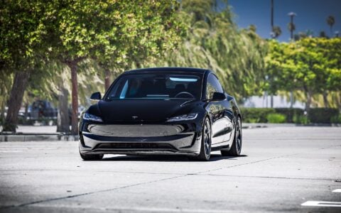 Tesla Model 3 Performance with 19-inch Satin Titanium UP-05 Forged Wheels by Unplugged Performance, parked in front of an industrial backdrop, highlighting the car’s sleek design and high-performance wheels.