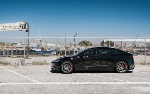 Tesla Model 3 Performance with 19-inch Satin Titanium UP-05 Forged Wheels by Unplugged Performance, parked in front of an industrial backdrop, highlighting the car’s sleek design and high-performance wheels.