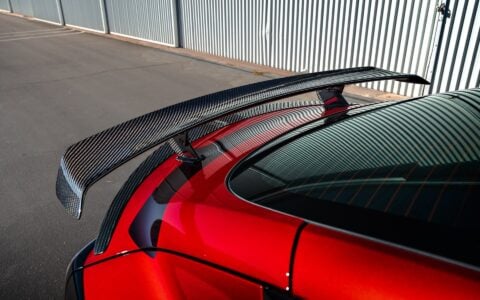 2024+ Tesla Model 3 Performance - Carbon Fiber Rear Spoiler with a trunk lip spoiler for added aerodynamics parked by a hangar