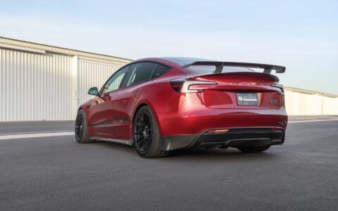 Rear view of a 2024+ Tesla Model 3 Performance parked displaying the UP Carbon Fiber Rear Sparts, Rear Diffuser Trim, Rear Dual Spoiler Wing, trunk spoiler and side skirts.