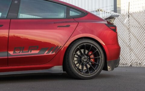 Side view of a 2024+ Tesla Model 3 Performance with Carbon Fiber Rear Sparts, Rear Dual Spoiler Wing and trunk spoiler and half of the side skirts on display.