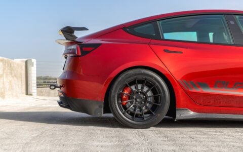 Side view of a 2024+ Tesla Model 3 Performance with Carbon Fiber Rear Sparts, Rear Dual Spoiler Wing and trunk spoiler and half of the side skirts showing.