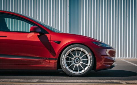 2024 Tesla Model 3 Performance in Ultra Red with UP-03 Pikes Peak Forged Wheels by Unplugged Performance, showcasing its aggressive stance and enhanced aerodynamics.