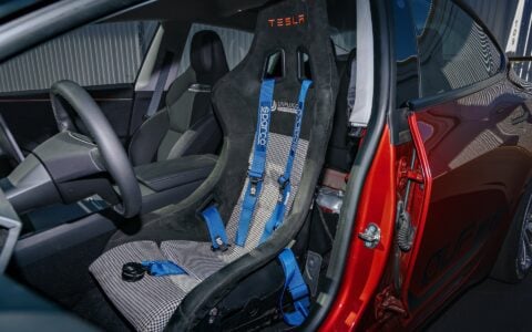 2024 Tesla Model 3 Performance in Ultra Red featuring a racing seat by Unplugged Performance parked.