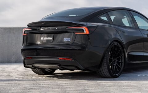 Rear view of a black Tesla Model 3 Performance featuring 21-inch Gloss Black UP-03 wheels by Unplugged Performance, parked on a rooftop parking lot under a partly cloudy sky.