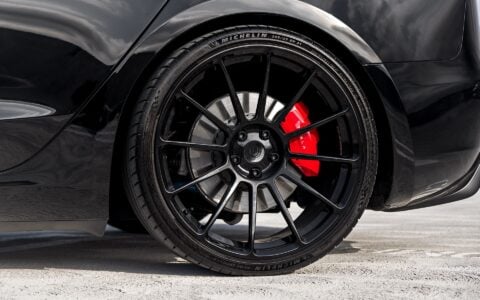 Close up show of a black Tesla Model 3 Performance featuring 21-inch Gloss Black UP-03 wheels by Unplugged Performance, parked.