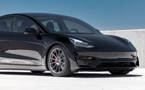 Front quarter view of a black Tesla Model 3 Performance, showcasing Satin Titanium UP-03 forged wheels. The car is parked in a parking lot and lowered with Unplugged Performance dual rate lowering springs in the low option.
