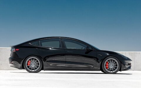 Side profile look of a Black Tesla Model 3 Performance, showcasing an aggressive stance achieved with Unplugged Performance dual rate lowering springs sitting on Satin Titanium UP-03 wheels.