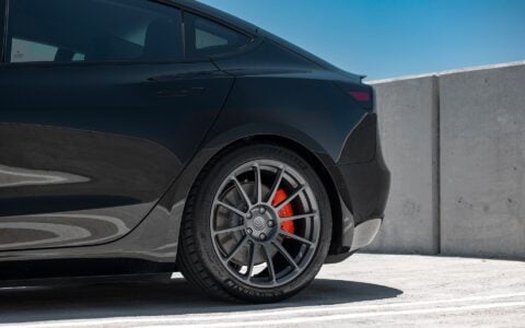 Black Tesla Model 3 Performance equipped with a carbon fiber rear high efficiency spoiler and Satin Titanium UP-03 forged wheels, designed for enhanced aerodynamics by Unplugged Performance.