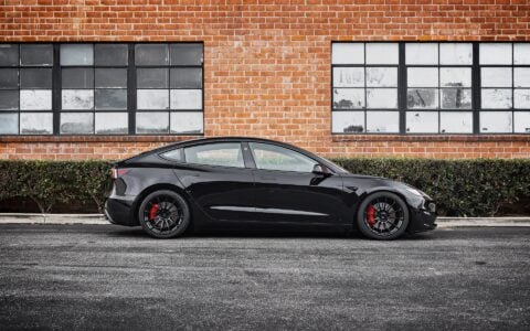 Side view of Tesla Model 3 Performance in an industrial setting, equipped with UP-03 Forged Wheels by Unplugged Performance, blending luxury and performance.