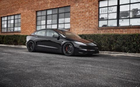 Tesla Model 3 Performance parked in an urban setting, equipped with UP-03 Forged Wheels by Unplugged Performance, offering a dynamic and aggressive appearance.
