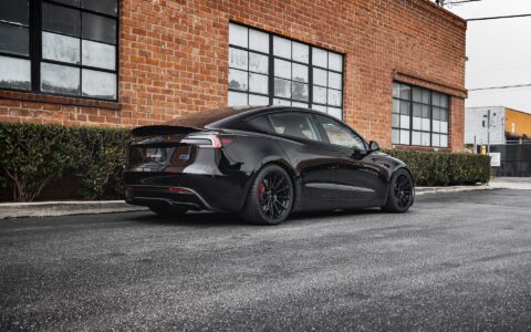 Tesla Model 3 Performance parked in an urban setting, equipped with UP-03 Forged Wheels by Unplugged Performance, offering a dynamic and aggressive appearance.