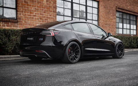 Rear shot of a Tesla Model 3 Performance parked in an urban setting, equipped with UP-03 Forged Wheels by Unplugged Performance, offering a dynamic and aggressive appearance.