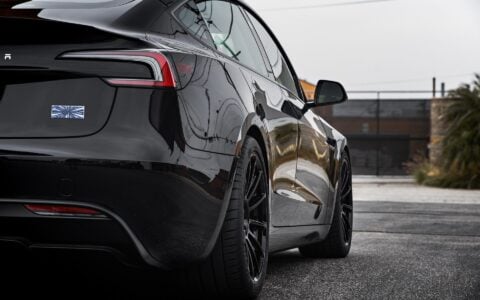 Tesla Model 3 Performance parked in an urban setting, equipped with UP-03 Forged Wheels by Unplugged Performance.