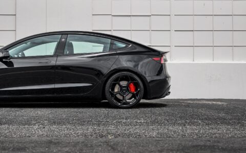 Rear side view of Tesla Model 3 Performance in an industrial setting, equipped with UP-03 Forged Wheels by Unplugged Performance, blending luxury and performance.