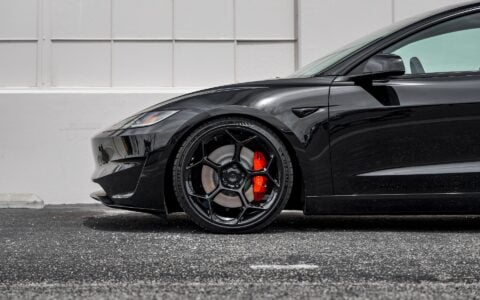 Close up side view of Tesla Model 3 Performance in an industrial setting, equipped with UP-03 Forged Wheels by Unplugged Performance, blending luxury and performance.