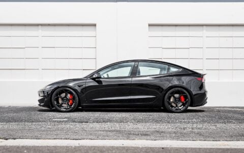 Side view of Tesla Model 3 Performance in an industrial setting, equipped with UP-05 Forged Wheels by Unplugged Performance.