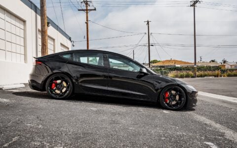 Side view of Tesla Model 3 Performance in an industrial setting, equipped with UP-05 Forged Wheels by Unplugged Performance, blending luxury and performance.