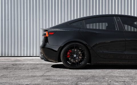 Detailed shot of the rear wheel on a Tesla Model 3 Performance showcasing UP X BBS Flugplatz Wheels in Gloss Black by Unplugged Performance, fitted with high-performance Yokohama Advan Apex tires.