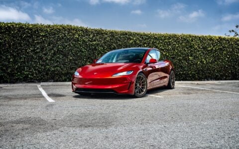 Front view of a parked 2024 Ultra Red Tesla Model 3 Performance, highlighting the 18-inch Satin Bronze UP-03 Forged Wheels by Unplugged Performance.