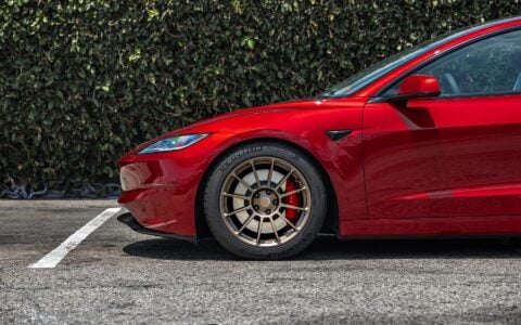 Detailed side view of the front wheel on a 2024 Tesla Model 3 Performance in Ultra Red, with 18-inch Satin Bronze UP-03 Forged Wheels by Unplugged Performance.