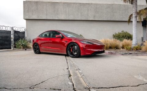 The image showcases an Ultra Red Tesla Model 3 Performance equipped with 20-inch Gloss Black UP-05 Forged Wheels by Unplugged Performance.