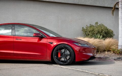 Ultra Red Tesla Model 3 Performance equipped with 20-inch Gloss Black UP-05 Forged Wheels by Unplugged Performance. The close-up view highlights the intricate wheel design and the vehicle's sleek profile.